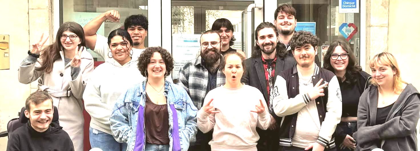 Groupe de personnes posant ensemble devant un bâtiment avec un panneau d'accueil.
