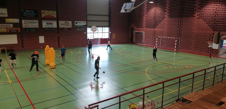 Salle de sport avec des joueurs s'entraînant au handball.