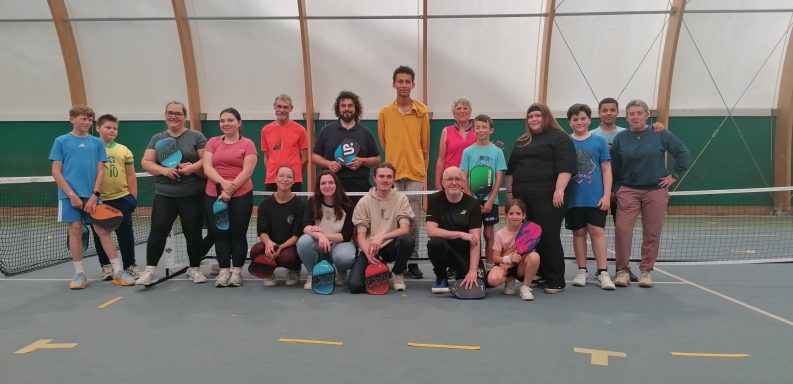 Groupe de personnes posant ensemble dans un court de tennis intérieur.