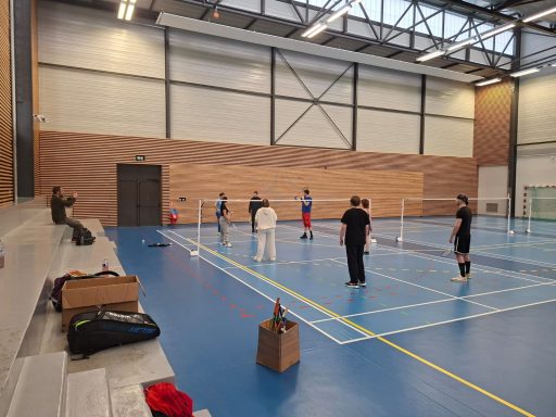 Des personnes s'entraînent au football en salle sur un terrain intérieur.