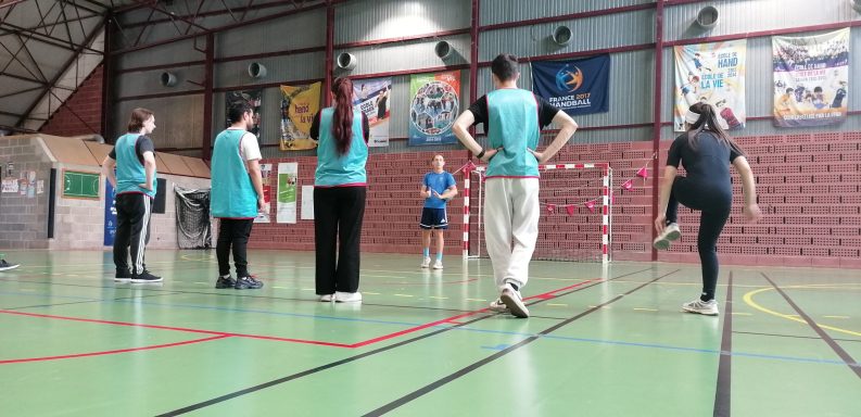 Groupe de personnes s'entraînant dans un gymnase, portant des maillots turquoise.